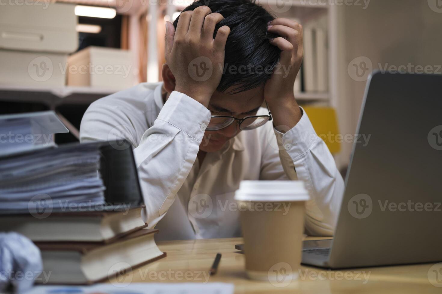 Asian young tired staff businessman using desktop computer having overwork project overnight in office. photo