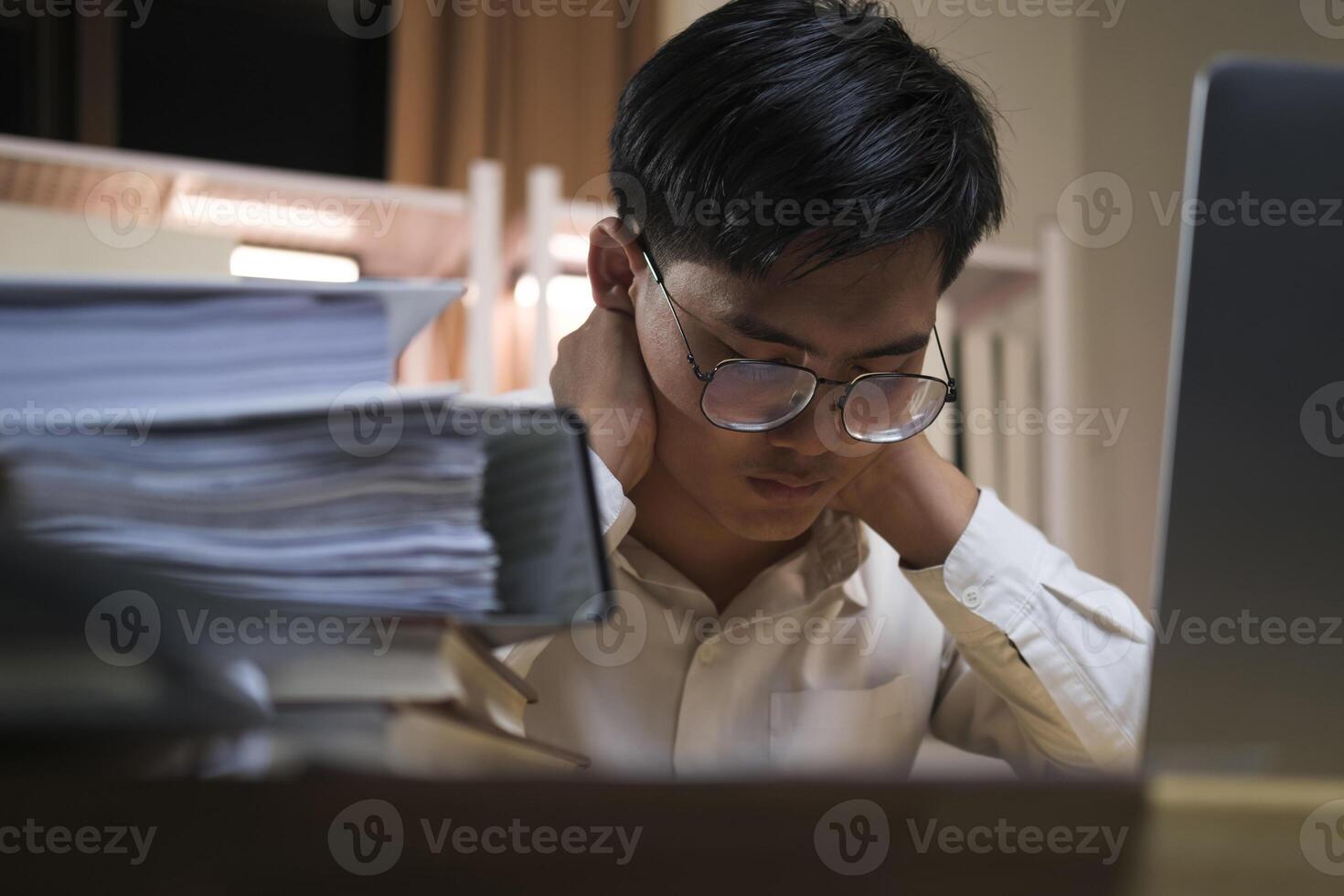 Asian young tired staff businessman using desktop computer having overwork project overnight in office. photo