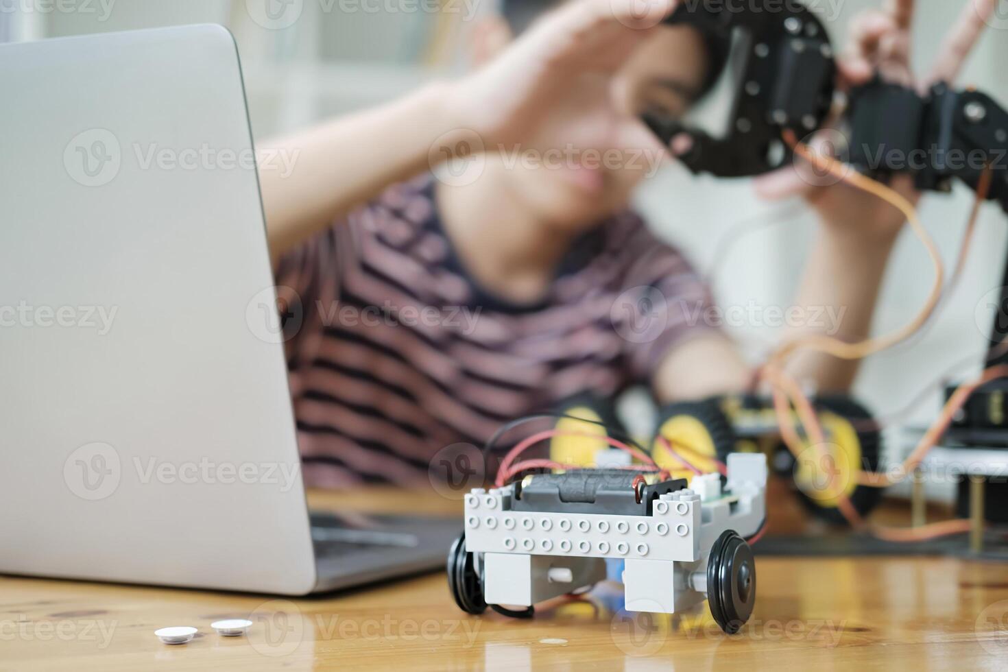 Asian teenager doing robot project in science classroom. technology of robotics programing and STEM education concept. photo