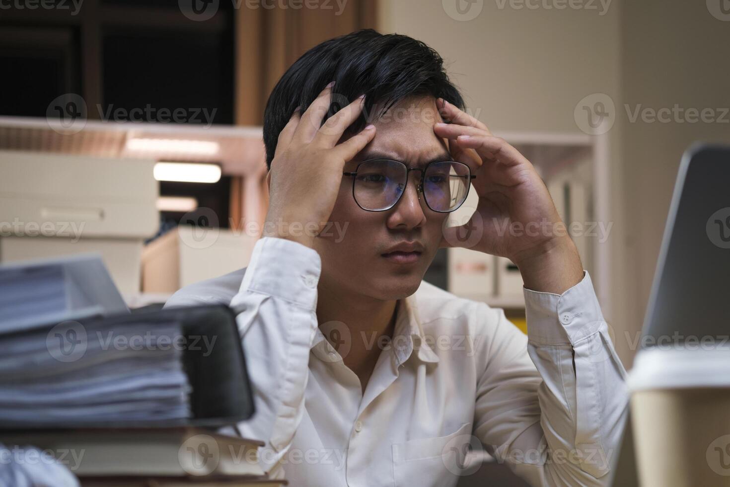 Asian young tired staff businessman using desktop computer having overwork project overnight in office. photo