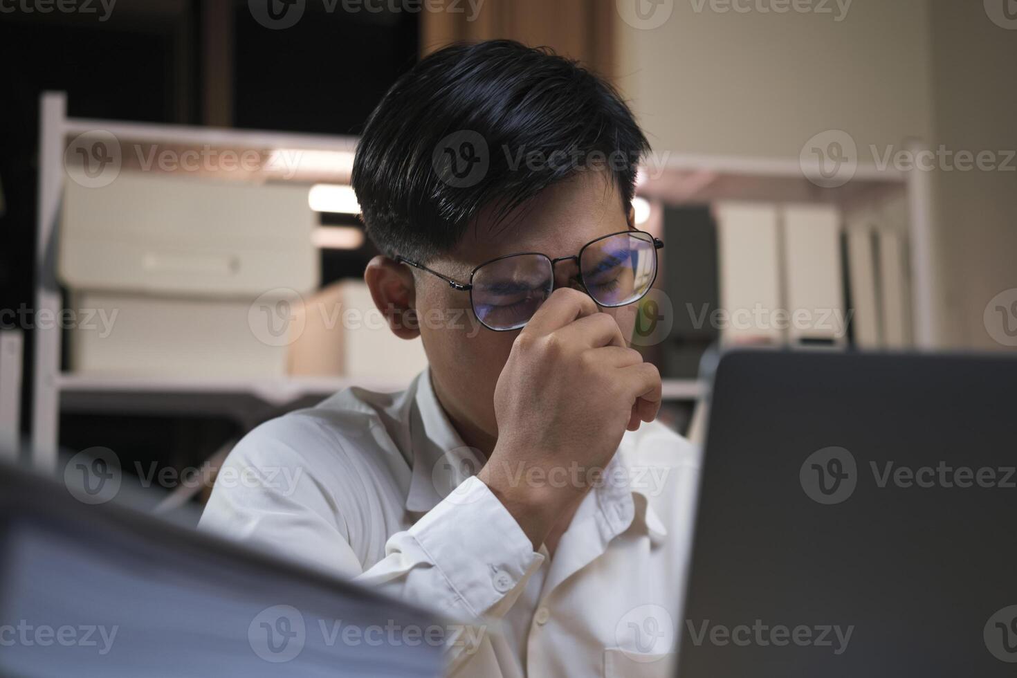 Exhausted young man with laptop in office. photo