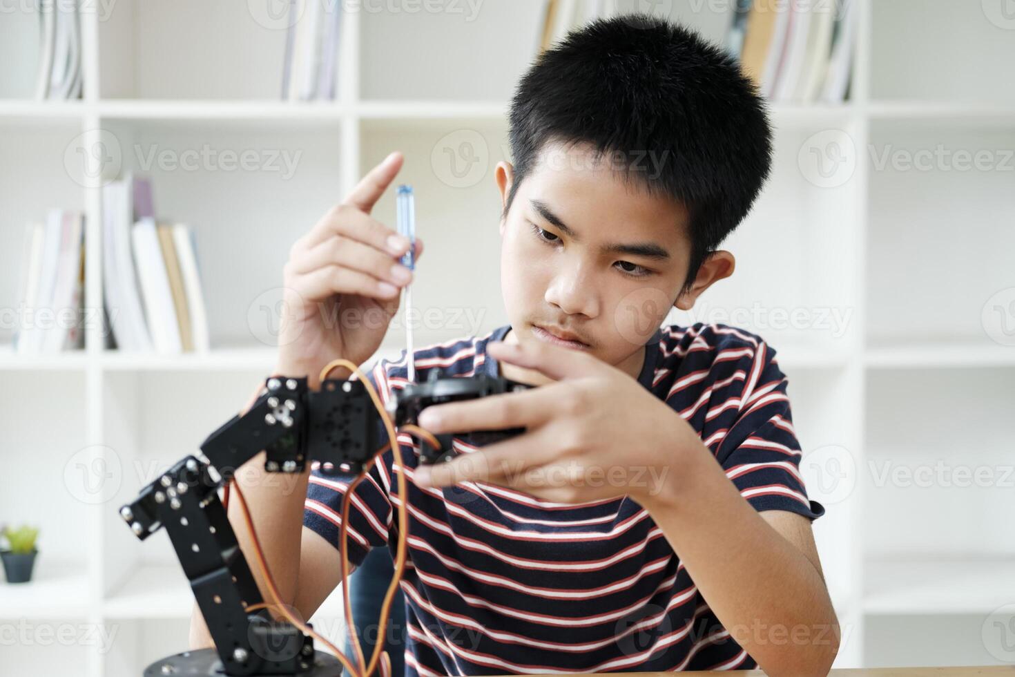 Asian teenager doing robot project in science classroom. technology of robotics programing and STEM education concept. photo