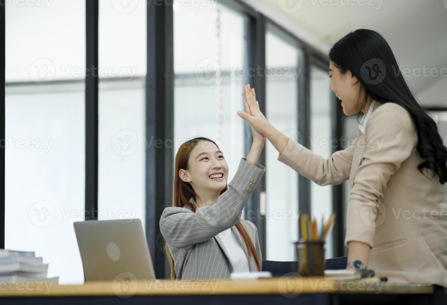 Two women are high-fiving with joy at their success in business. and celebrate performance and teamwork. photo