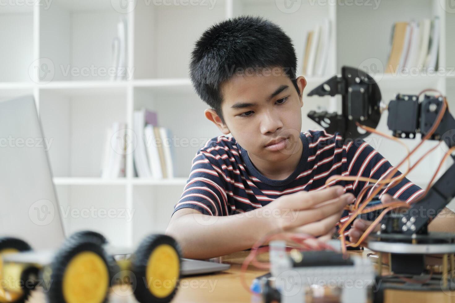 Asian teenager doing robot project in science classroom. technology of robotics programing and STEM education concept. photo