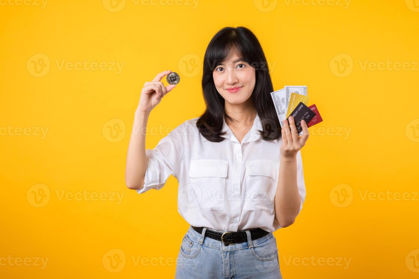 Capture the essence of digital currency with stunning portrait of young Asian woman confidently holds digital currency, cash, credit card, and smartphone. The digital currency concept. photo