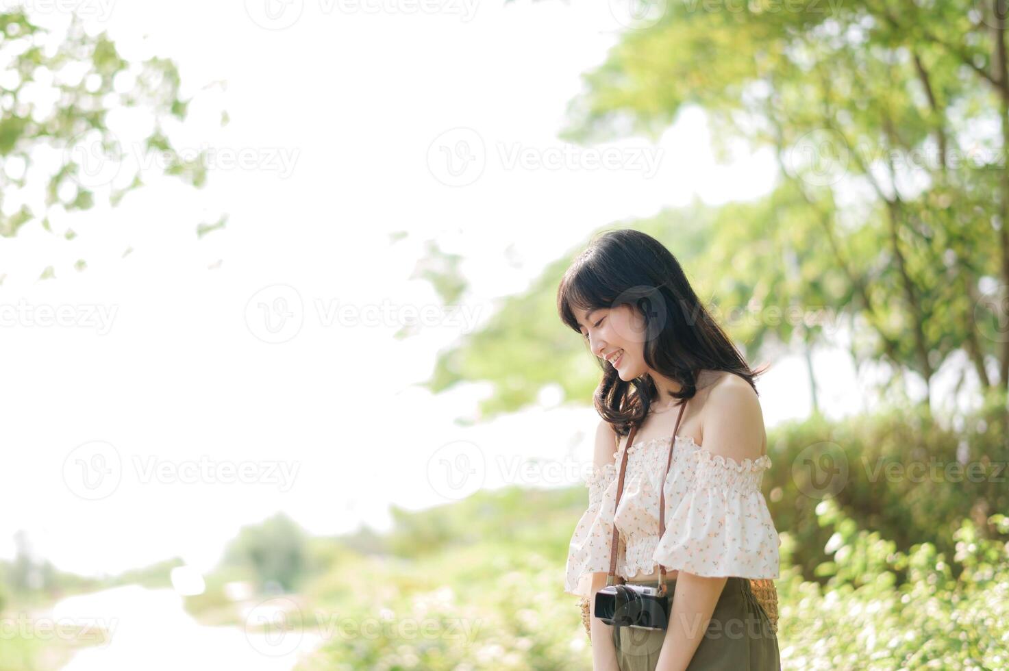 Portrait of asian young woman traveler with weaving hat and basket and a camera on green public park nature background. Journey trip lifestyle, world travel explorer or Asia summer tourism concept. photo