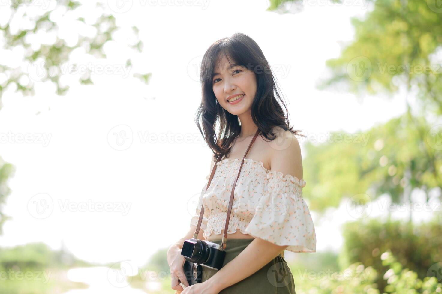 Portrait of asian young woman traveler with weaving hat, basket, mobile phone and camera on green public park background. Journey trip lifestyle, world travel explorer or Asia summer tourism concept. photo