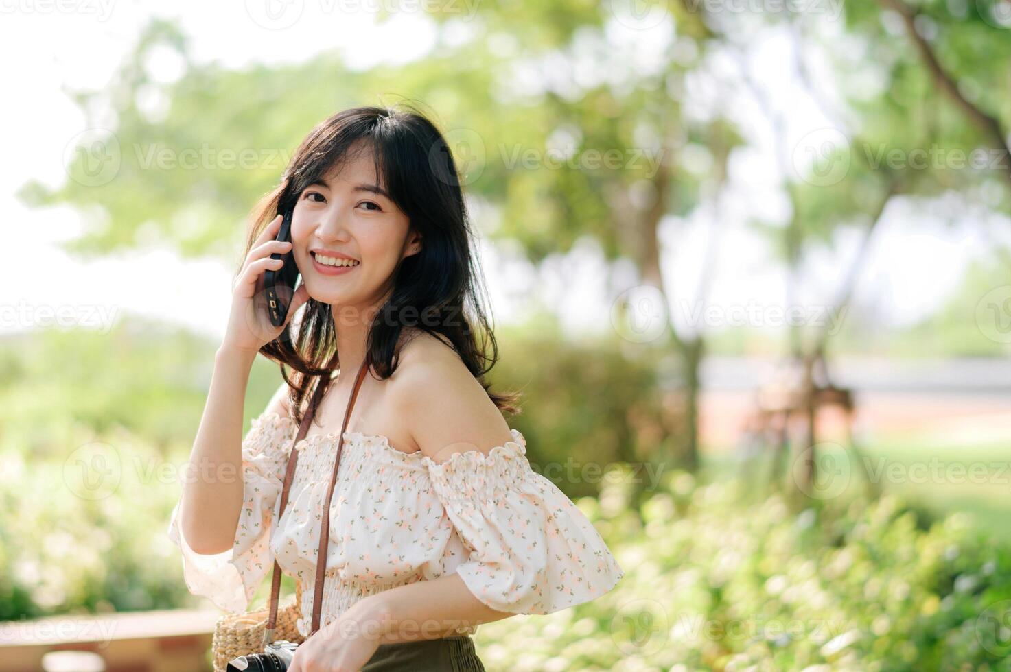 Portrait of asian young woman traveler with weaving hat, basket, mobile phone and camera on green public park background. Journey trip lifestyle, world travel explorer or Asia summer tourism concept. photo