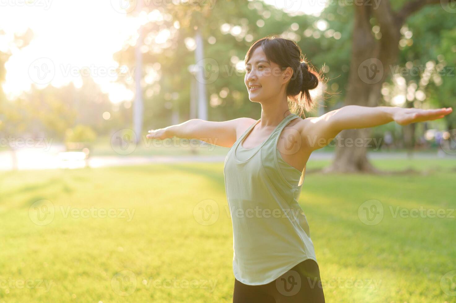 Female jogger. Fit young Asian woman with green sportswear stretching muscle in park before running and enjoying a healthy outdoor. Fitness runner girl in public park. Wellness being concept photo