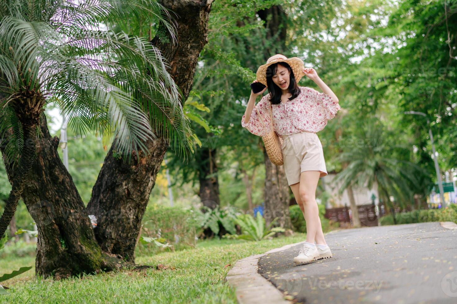 Portrait of asian young woman traveler with weaving hat and basket happy smile on green public park nature background. Journey trip lifestyle, world travel explorer or Asia summer tourism concept. photo