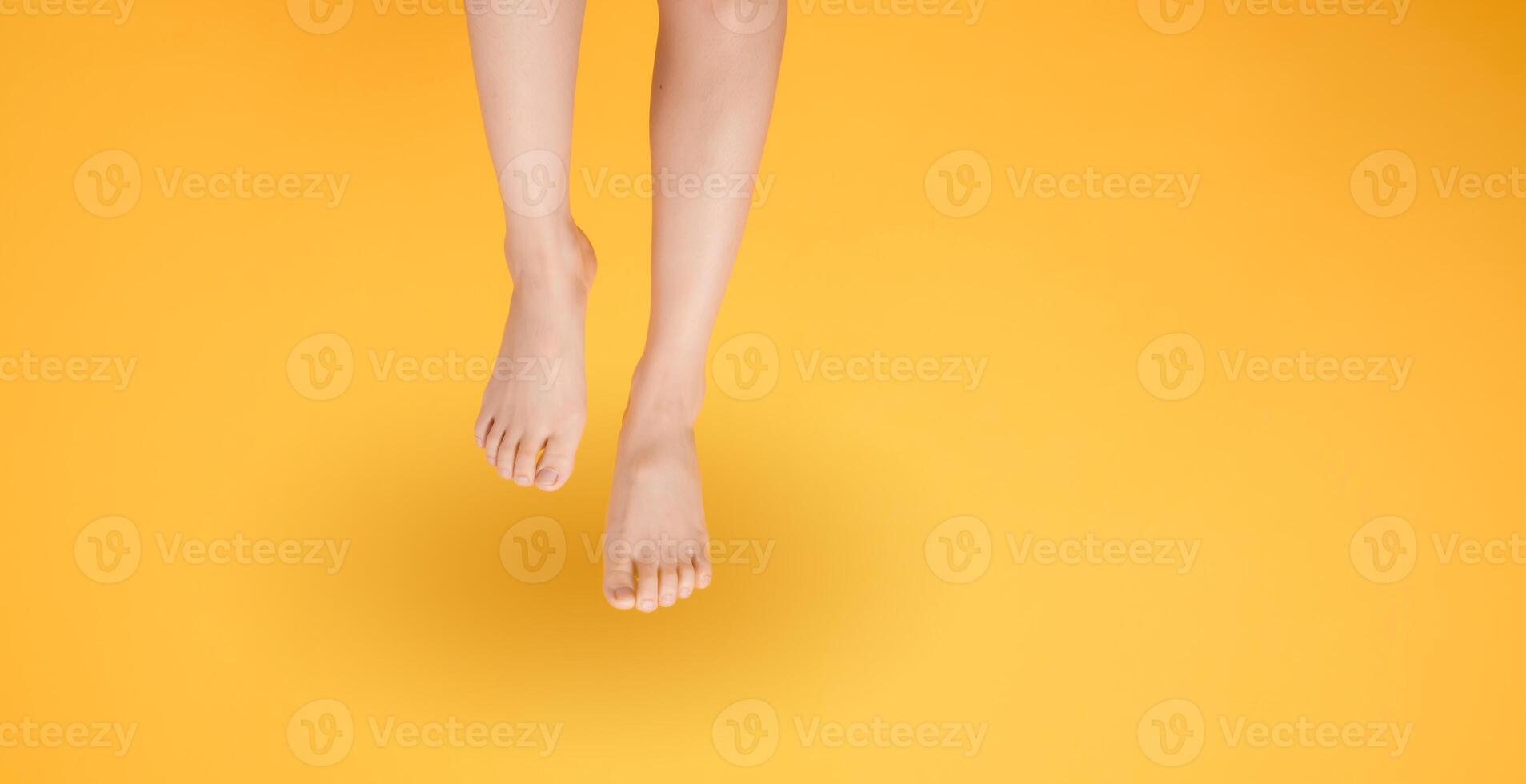 Capture the essence of smooth and soft touch with 30s person elegant close up. Features woman's legs isolated on vibrant yellow background, conveying the concept of gentle and velvety foot touch. photo