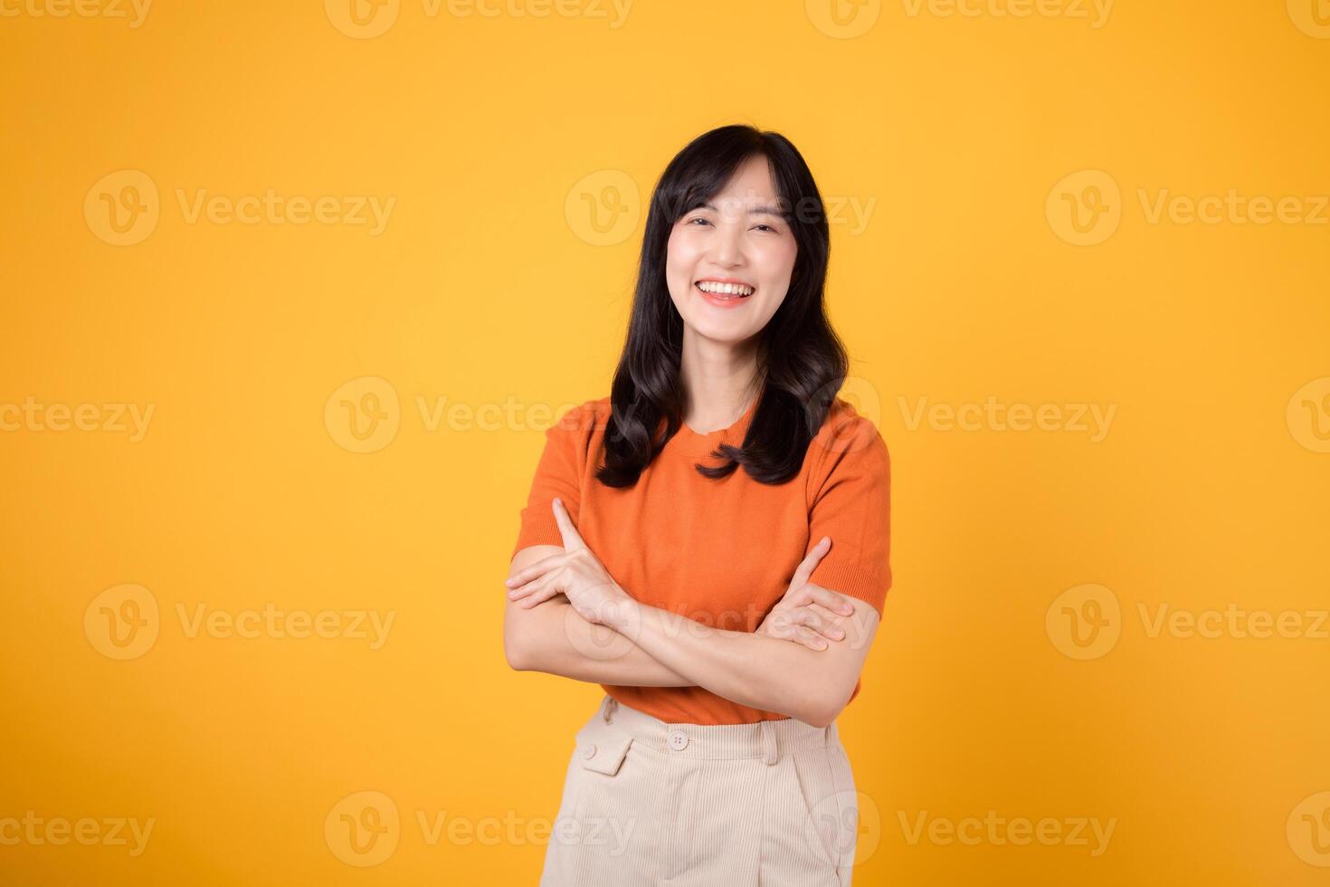 portrait cute attractive young 30s businesswoman happy smile face showing arm crosses expression successful business work isolated on yellow background. photo