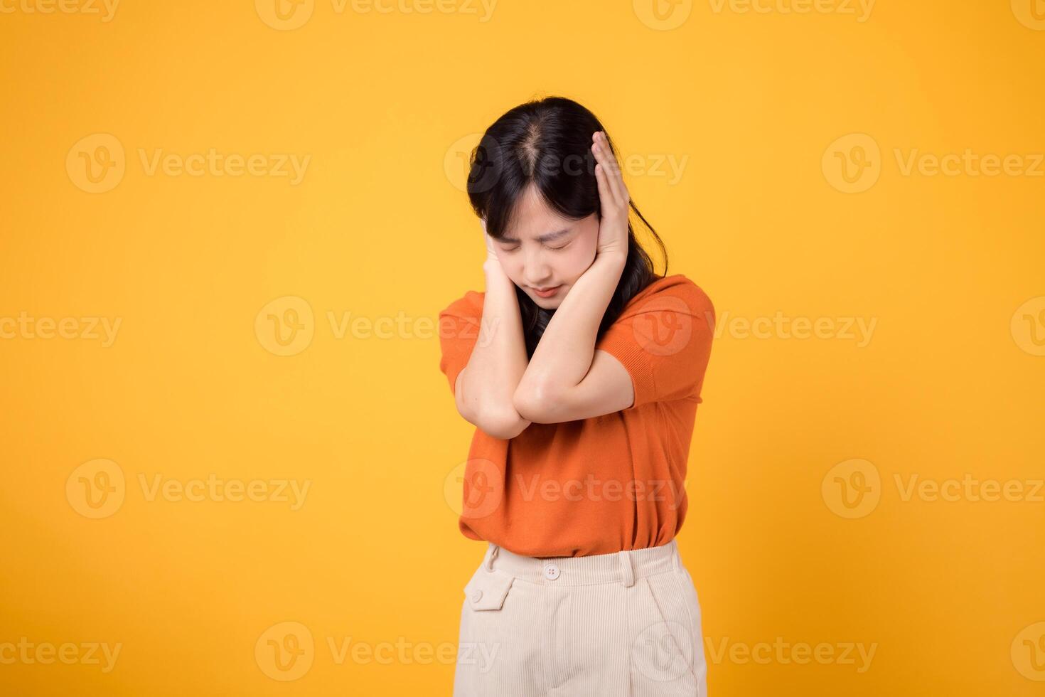 retrato joven 30s asiático mujer expresión desesperado emocional estrés sensación con cerrado oído con mano para silencio a oír un ruido sonido en contra amarillo antecedentes. infeliz desesperado gesto concepto. foto