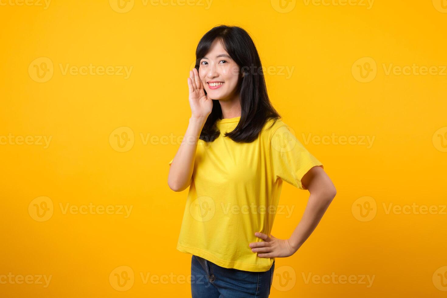 Portrait of a Young Asian Woman with Shout Hands Gesture Isolated on Yellow Studio Background photo