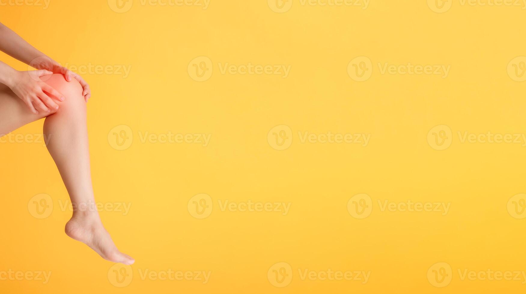 Discover knee pain relief and legs healthcare with woman's hands holding her painful knee on a vibrant yellow background. photo