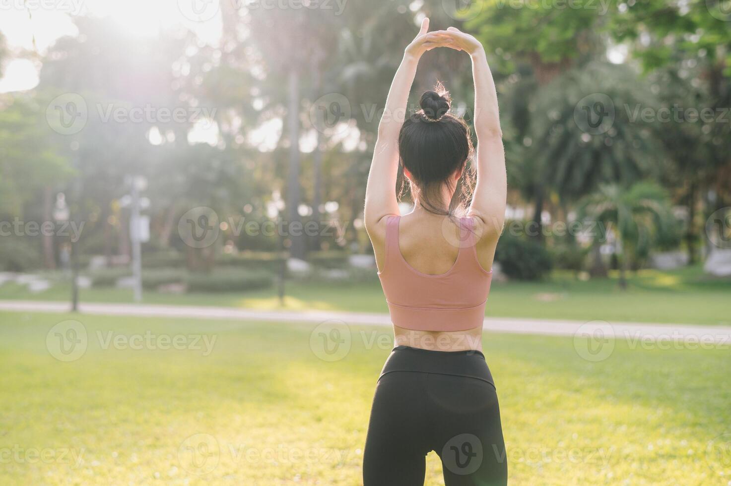 bienestar y sano estilo de vida retrato 30s asiático mujer en rosado ropa de deporte. preparando y extensión brazo músculos antes de puesta de sol correr en el parque. aptitud fuera de y equilibrado vida concepto. foto