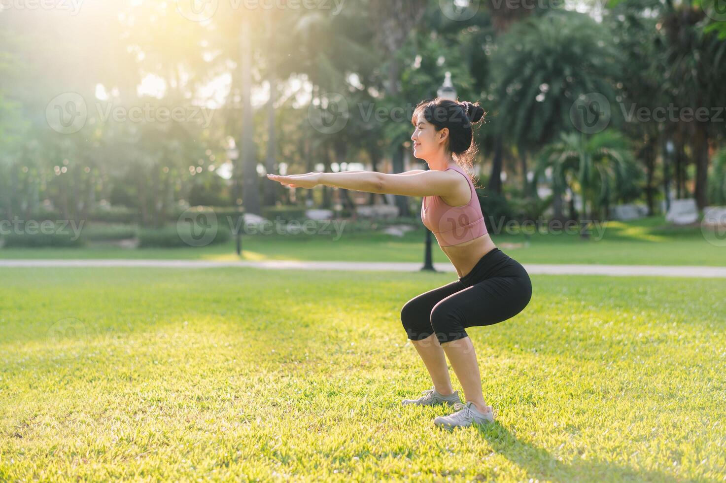 sano al aire libre estilo de vida con ajuste joven asiático mujer 30s vistiendo rosado ropa de deporte ponerse en cuclillas músculos en público parque antes de yendo para vigorizante correr, encarnando el bienestar concepto. foto