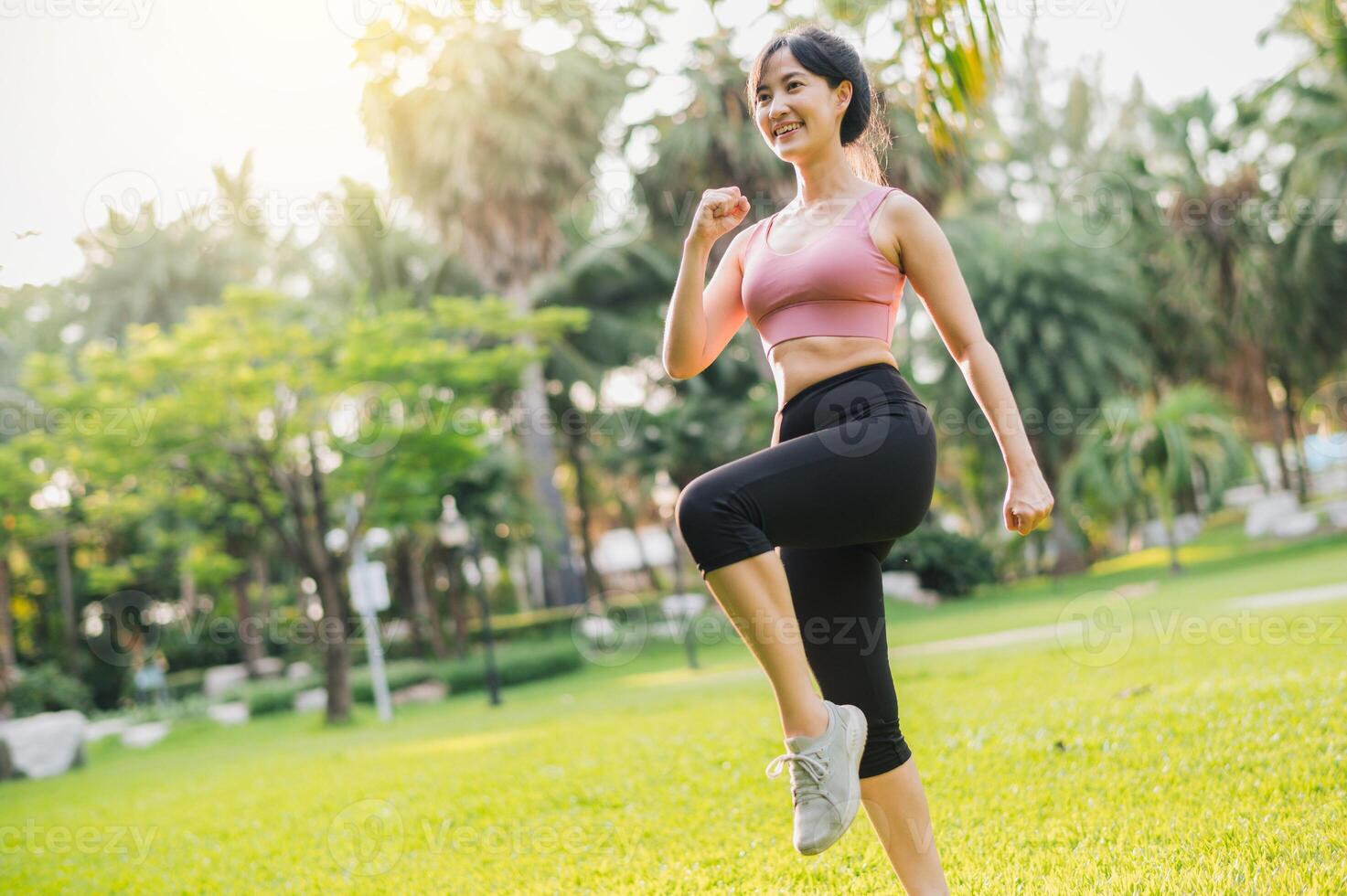 sumergirse tú mismo en concepto de bienestar y bienestar. ajuste asiático mujer en 30, vistiendo rosado ropa de deporte, hacer ejercicio en público parque a puesta de sol. inspirador monitor de un sano al aire libre estilo de vida. foto