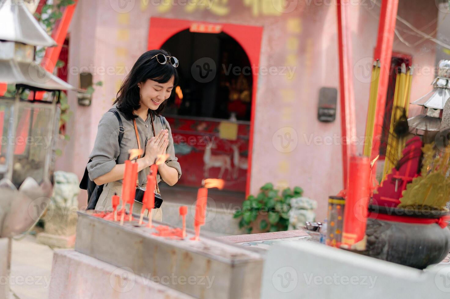 Portrait of asian woman saying prayers and eyes close in front of local Chinese shrine in Bangkok, Thailand photo
