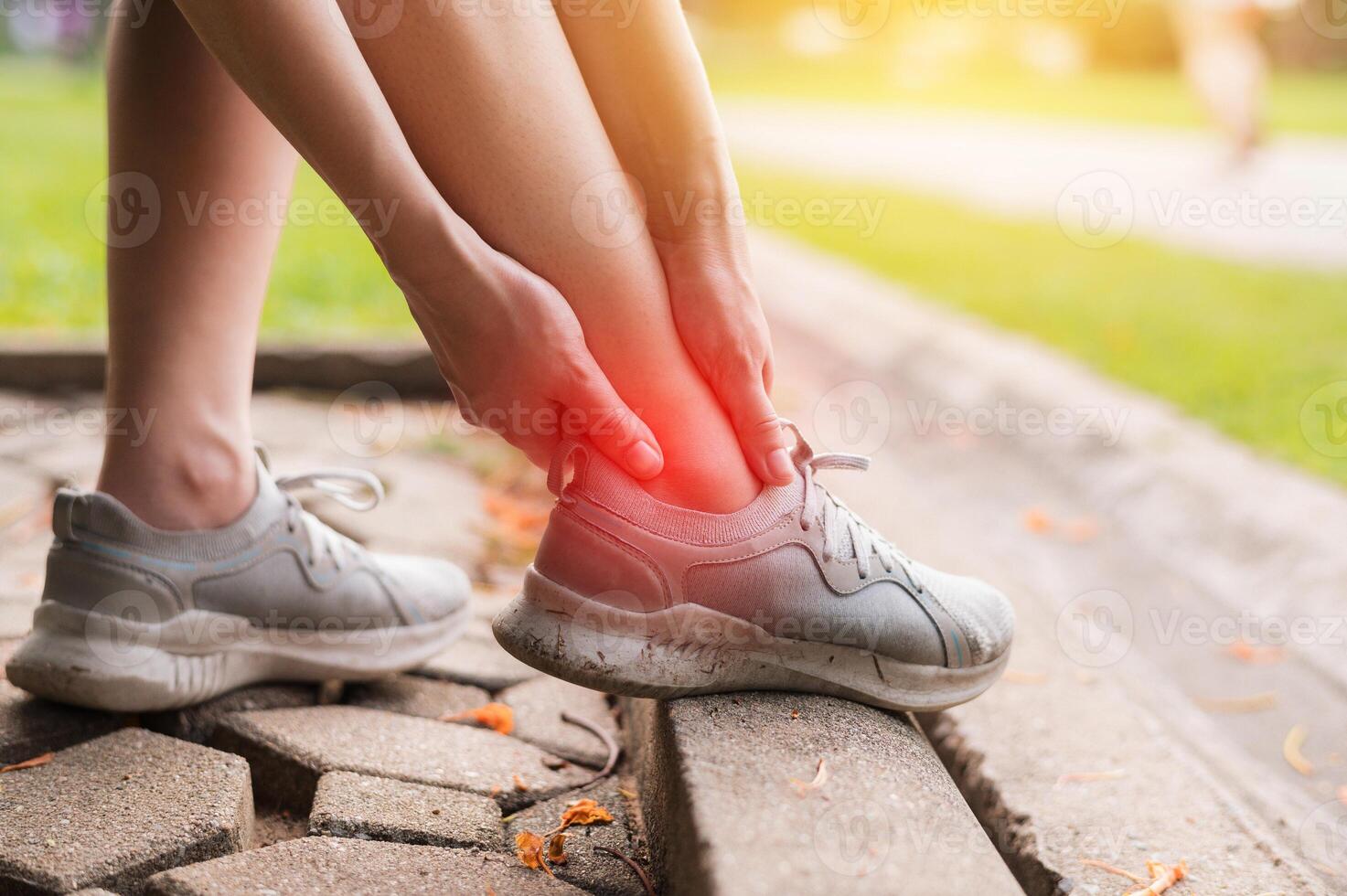 female joggers, pain and discomfort after running in the public park. care and treatment for ankle injuries concept. photo