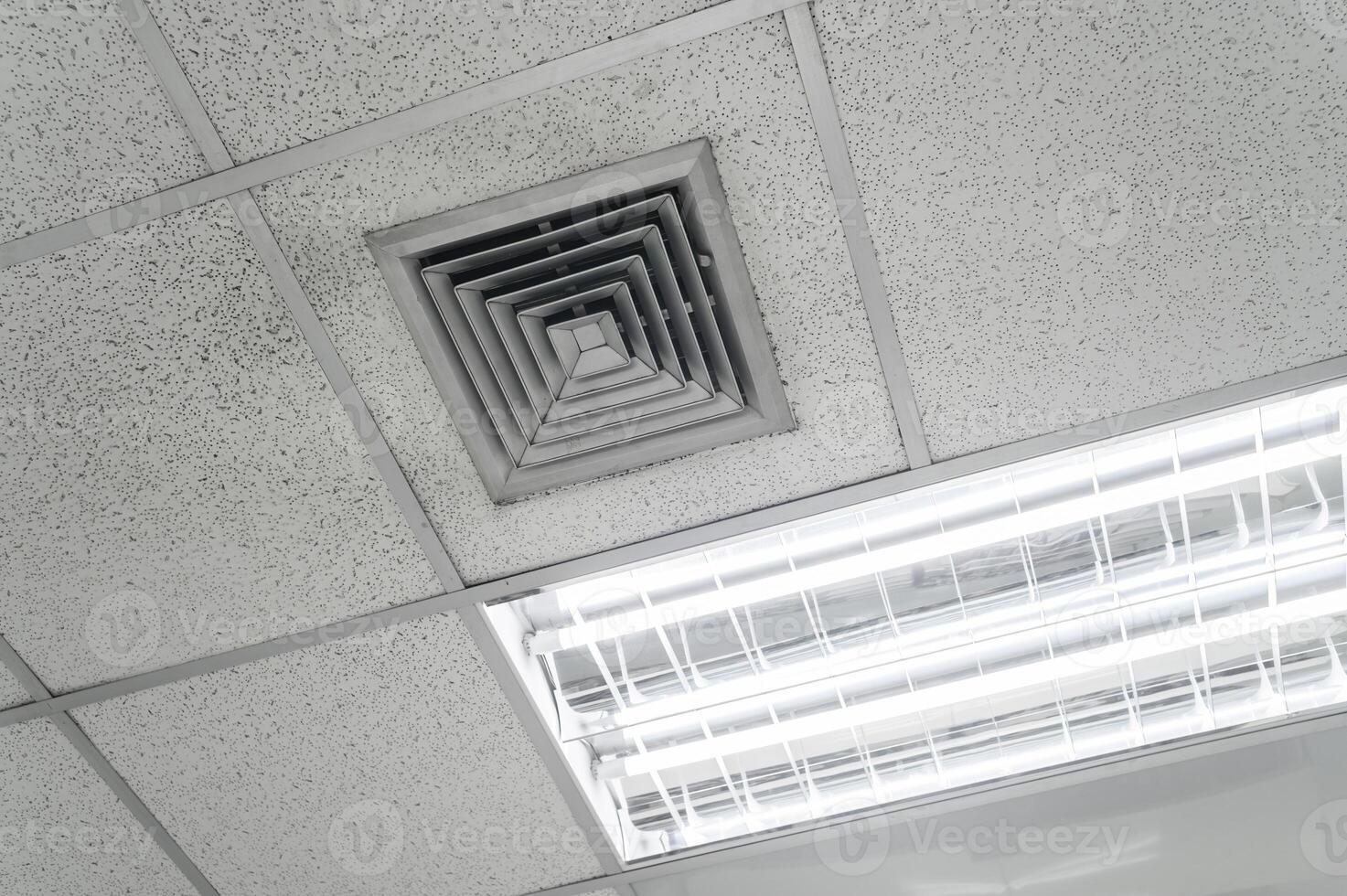 Ceiling mounted cassette type air conditioner and modern lamp light on white ceiling. Duct air conditioner for home, hall or office. photo