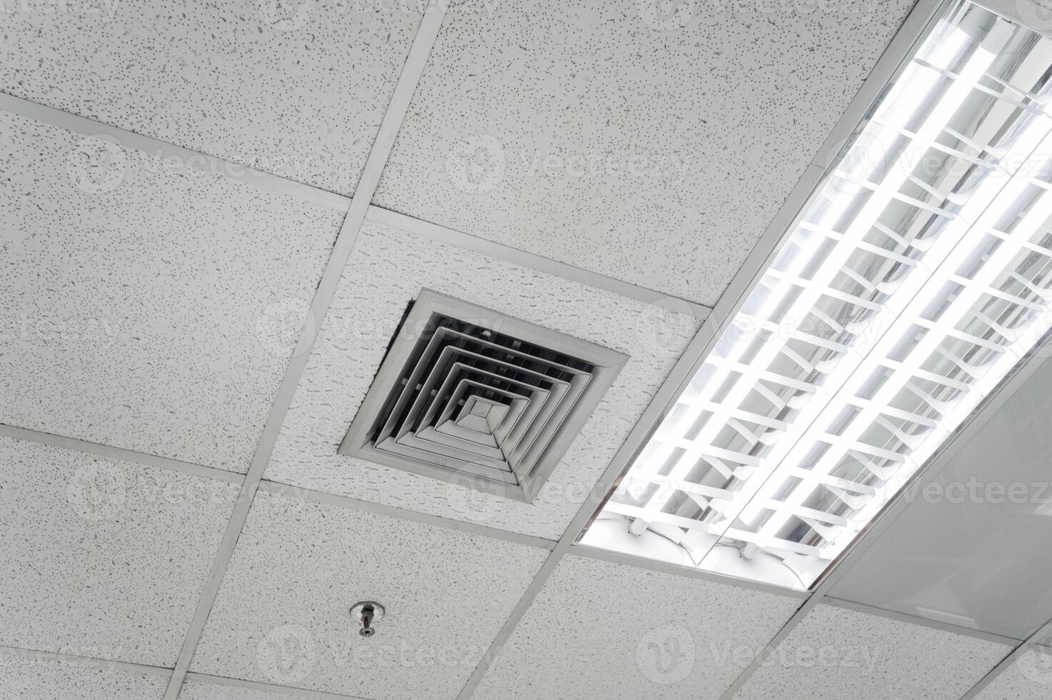 Ceiling mounted cassette type air conditioner and modern lamp light on white ceiling. Duct air conditioner for home, hall or office. photo