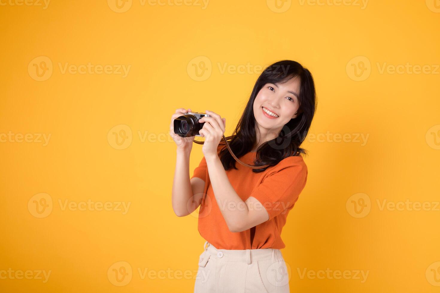 Vibrant traveler capturing moments with a camera isolated on yellow background. Adventure and exploration concept. photo