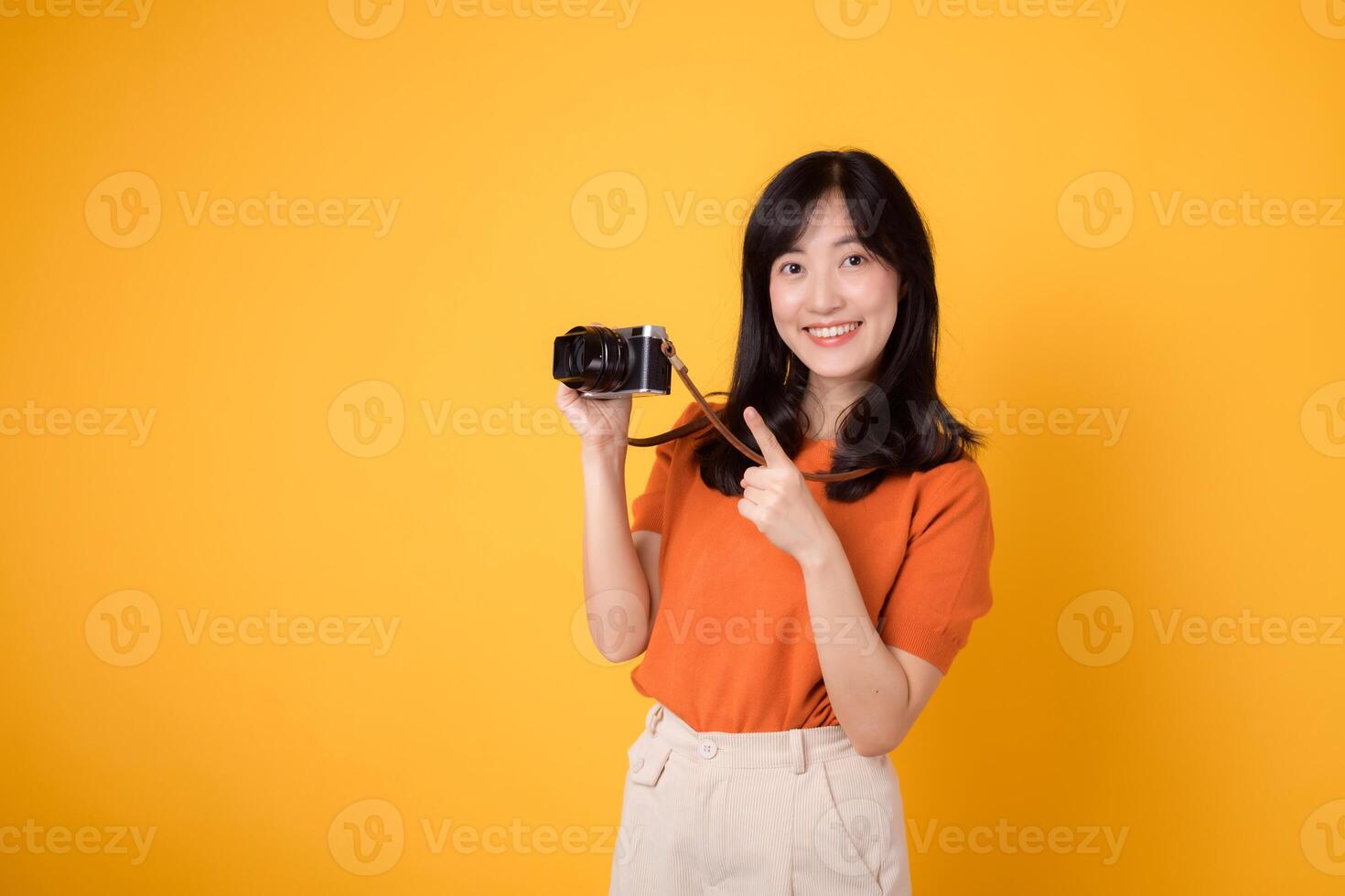 vibrante mujer con un cámara aislado en amarillo fondo, demostración el aventuras de explorador nuevo lugares en su vacaciones. foto