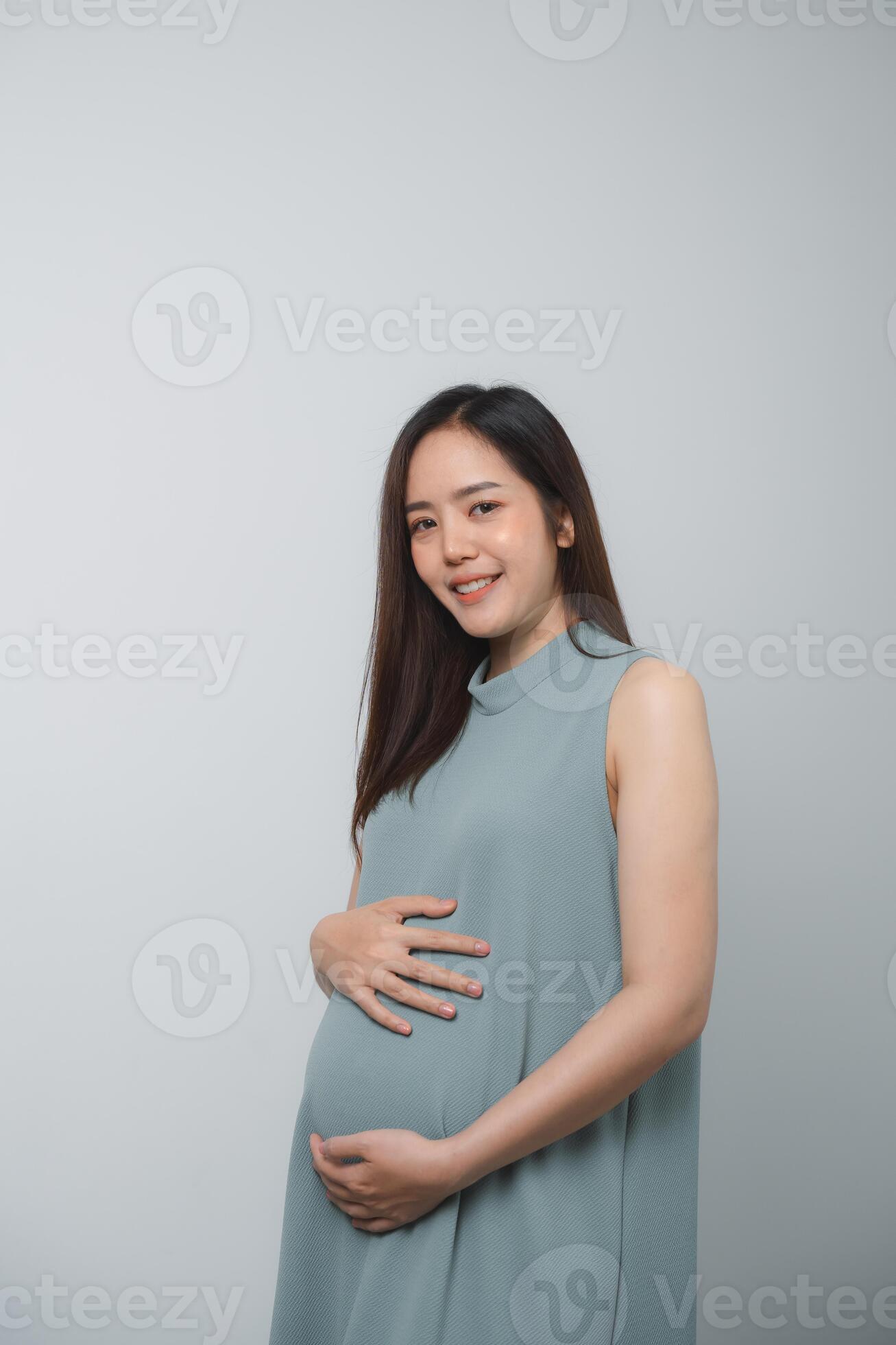Pregnant woman holding on her belly making hand heart shape isolated on