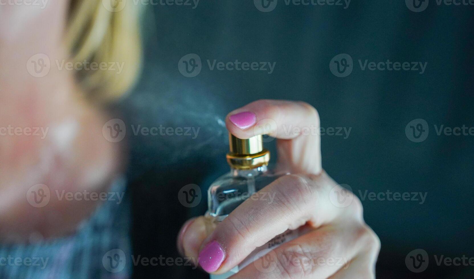 Woman spraying perfume. Woman holding bottle of perfume. photo