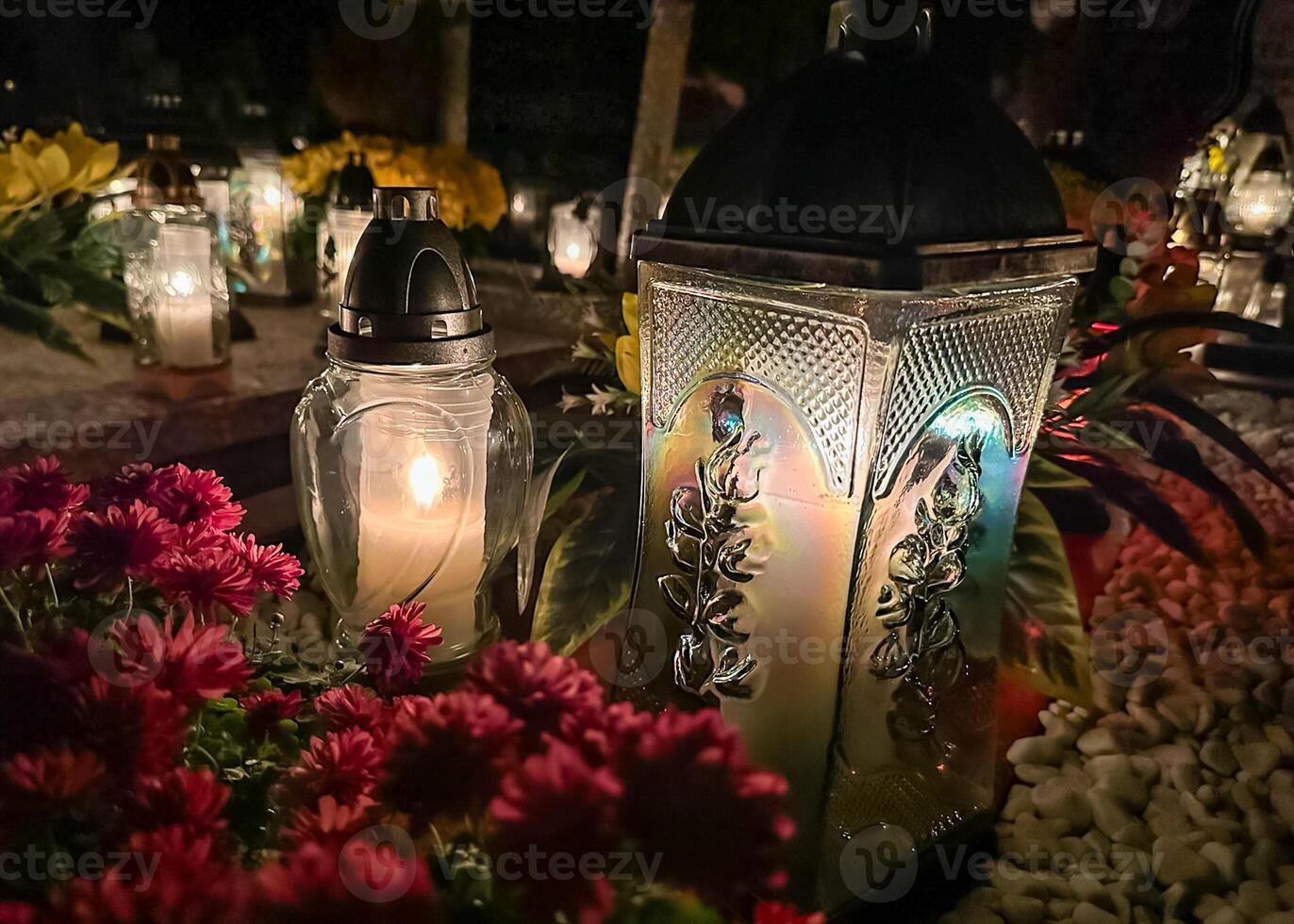 Grave candles on the grave during the all saints day. Cemetery candles with beautiful lights and flowers. Graveyard during the all souls day. photo