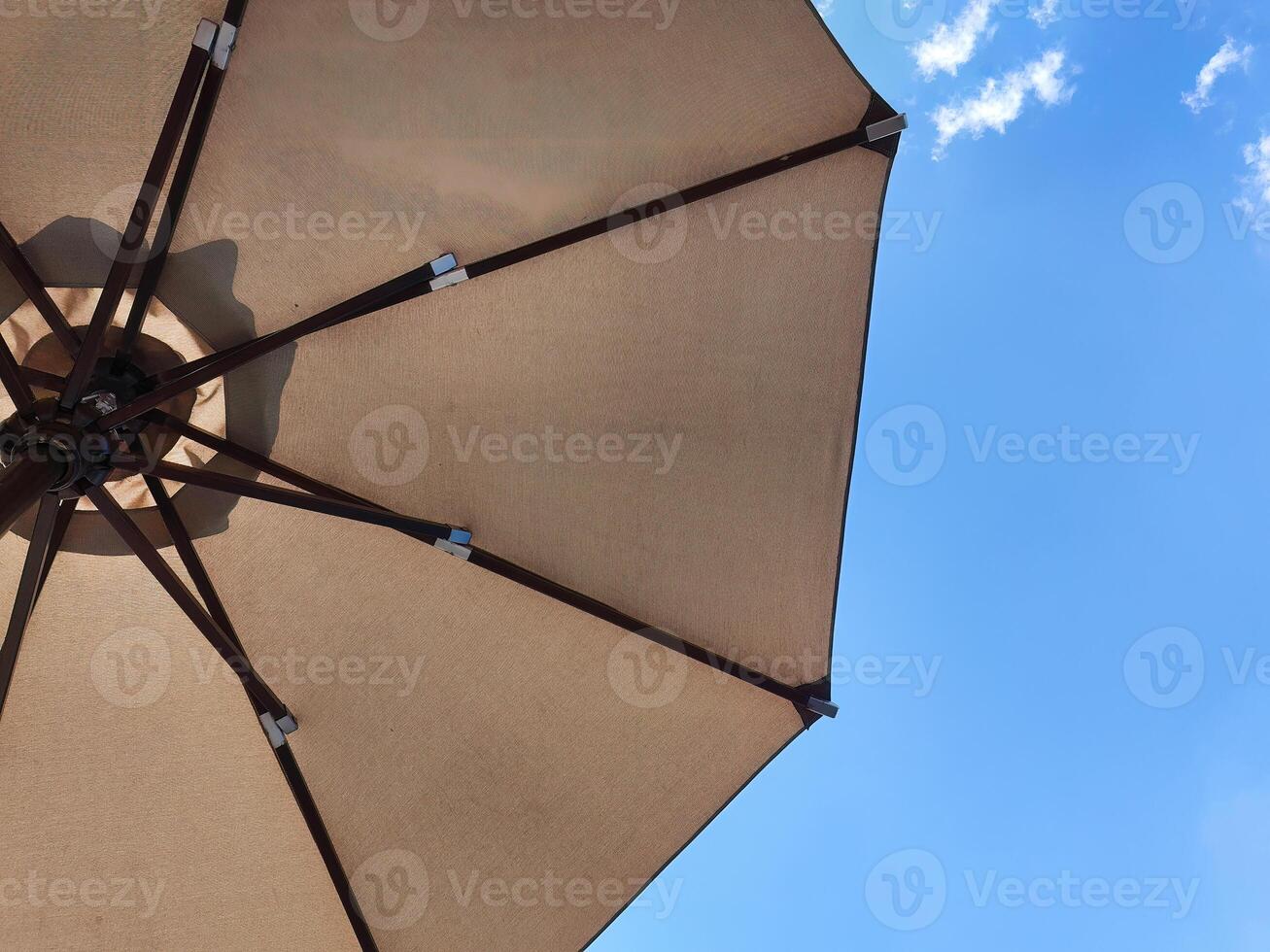 Low angle view of an opened beach fabric umbrella against the blue sunny sky, view from under parasol, holiday or vacation concept, with copy space photo