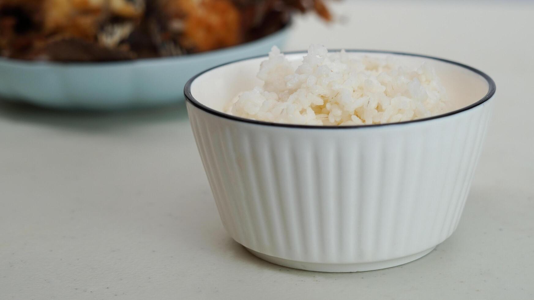 White rice in a bowl and fried fish on a white plate are served on the table photo