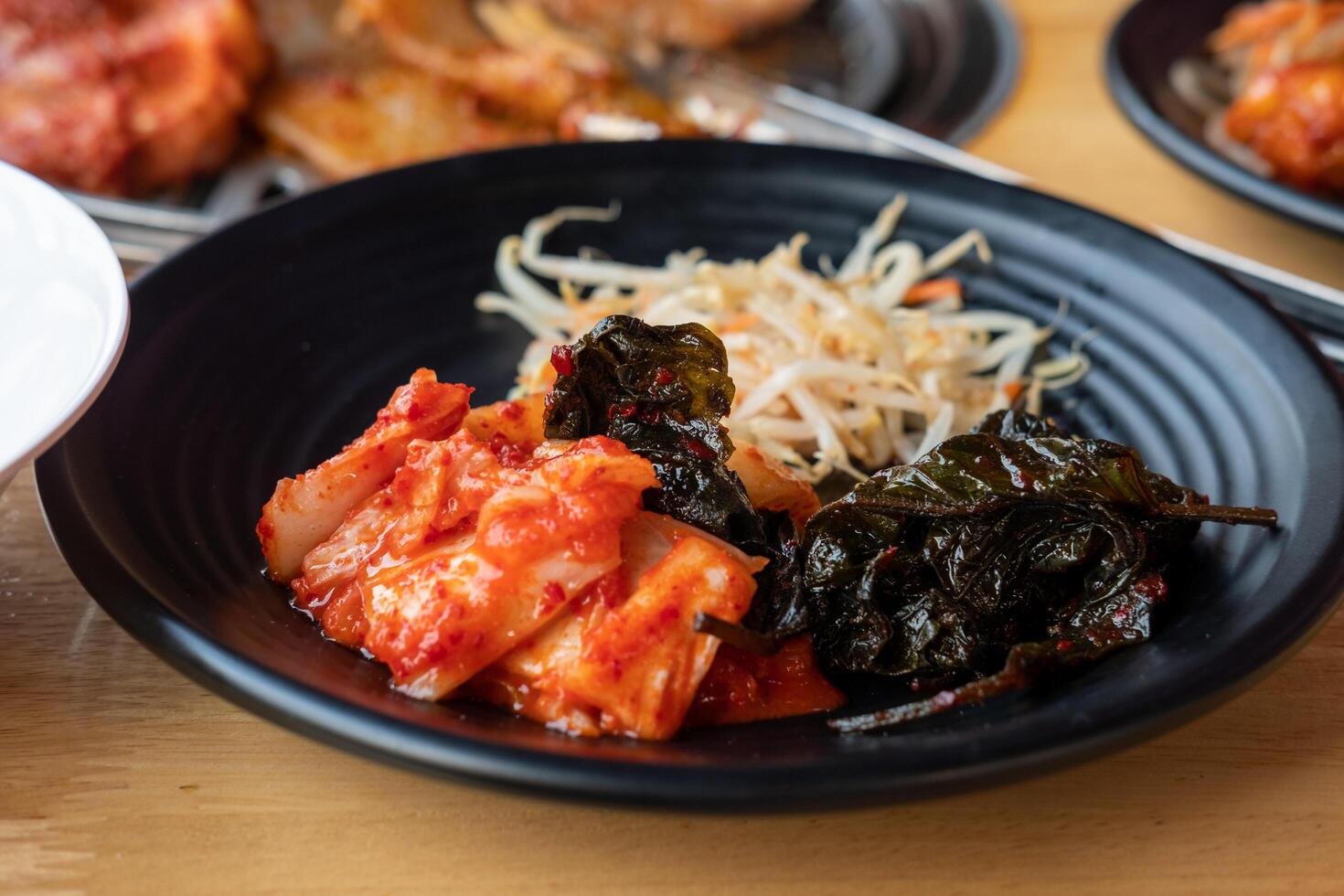 Korean side dishes, kimchi, seasoned bean sprouts, sesame leaves marinated in sauce photo