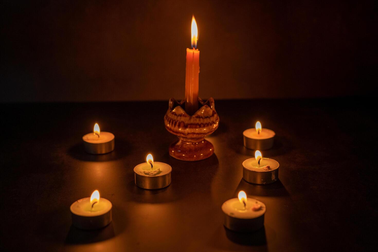 Many candles lit against a black background.Burning candles on dark tableMemory photo