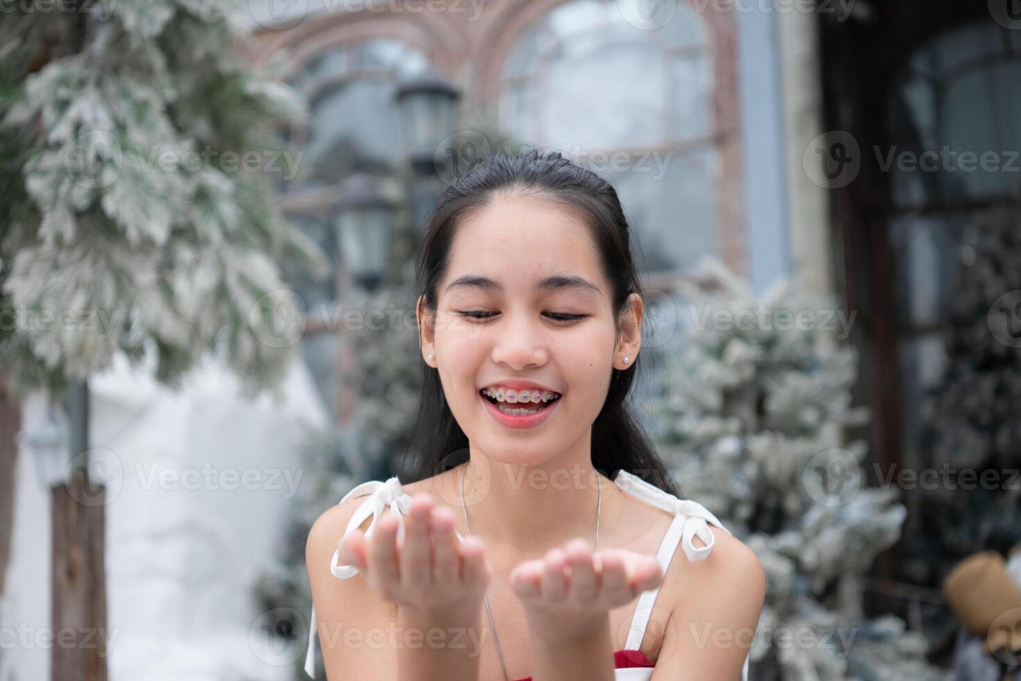 Portrait of teenage girl in a red dress relaxed and smiling in a snowy yard. photo
