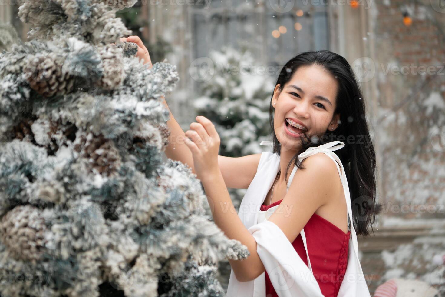 Portrait of teenage girl in a red dress relaxed and smiling in a snowy yard. photo