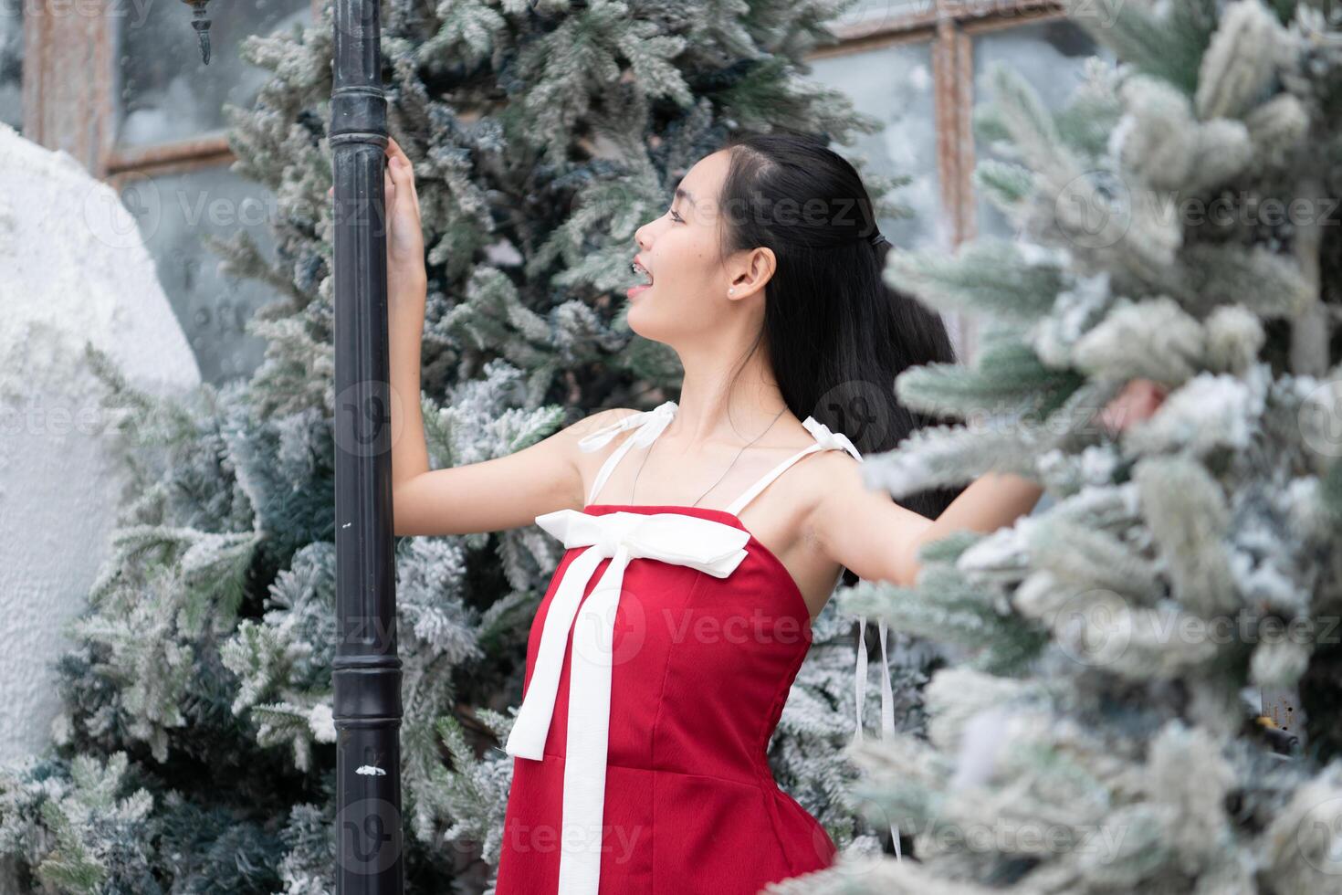 Portrait of teenage girl in a red dress relaxed and smiling in a snowy yard. photo