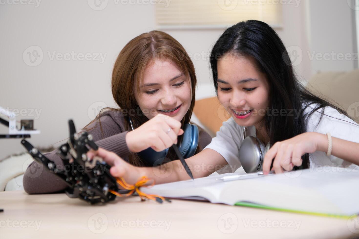 retrato de Adolescente muchachas estudiantes estudiando con robot modelo en el vivo habitación foto