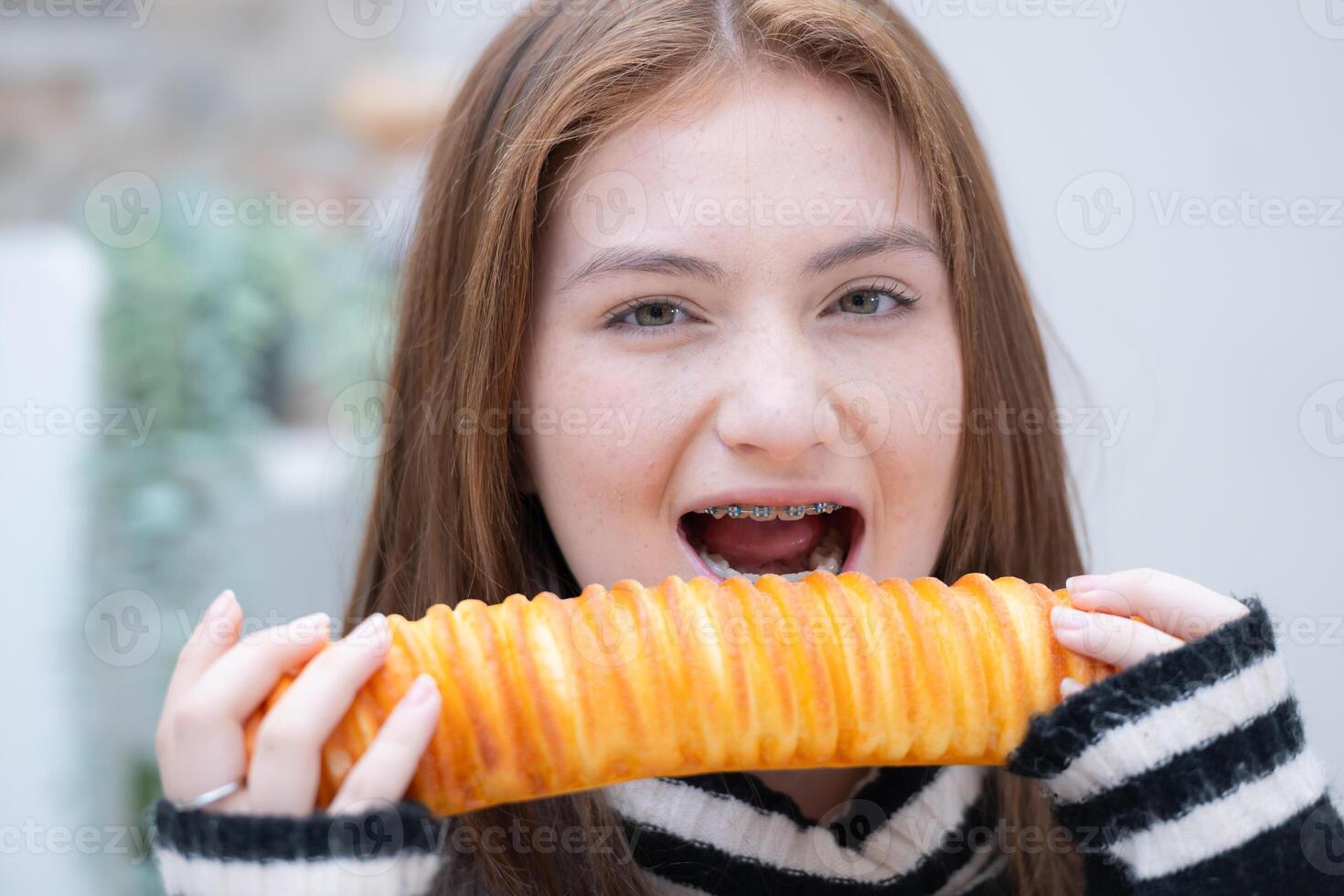 retrato de Adolescente niña comiendo un pan en el cocina a hogar foto