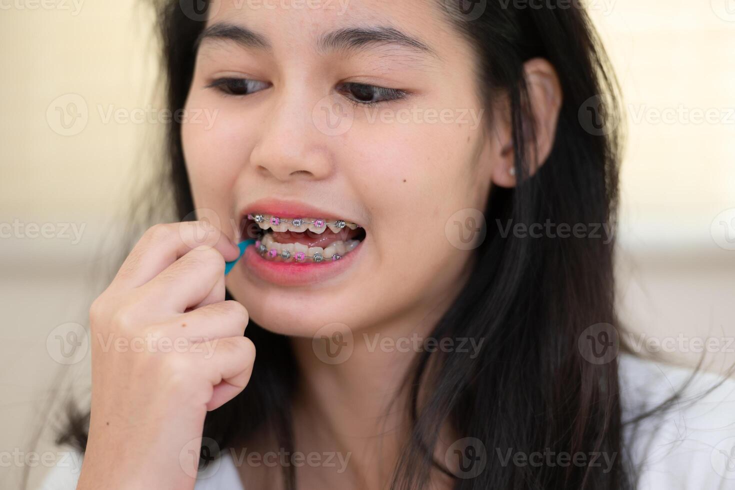 retrato de un joven asiático mujer con tirantes en su dientes foto