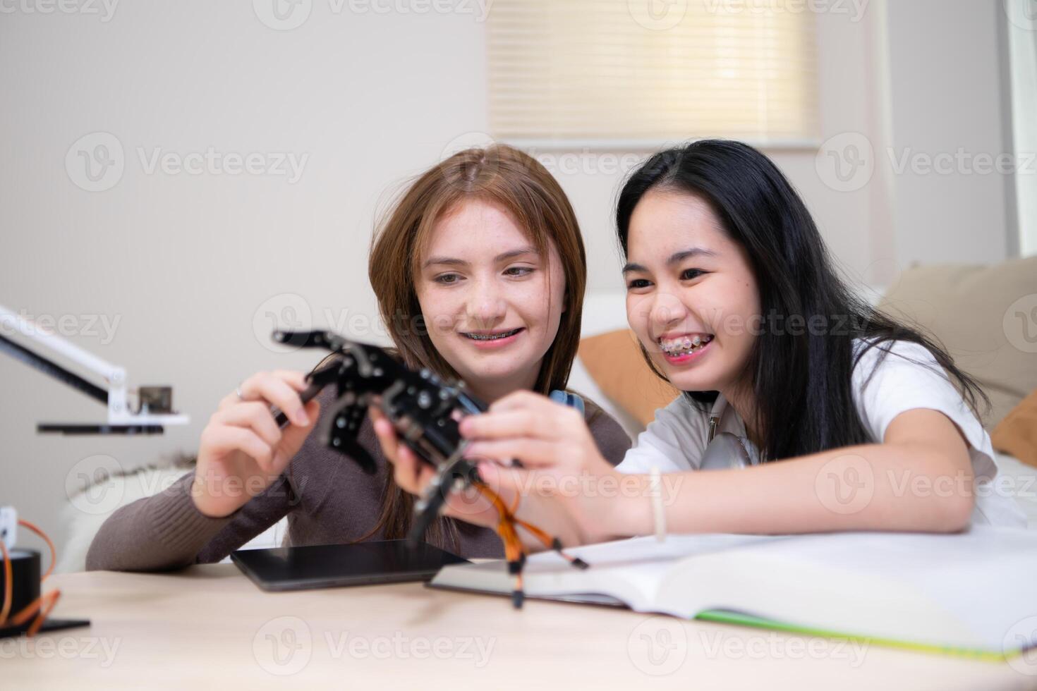 retrato de Adolescente muchachas estudiantes estudiando con robot modelo en el vivo habitación foto