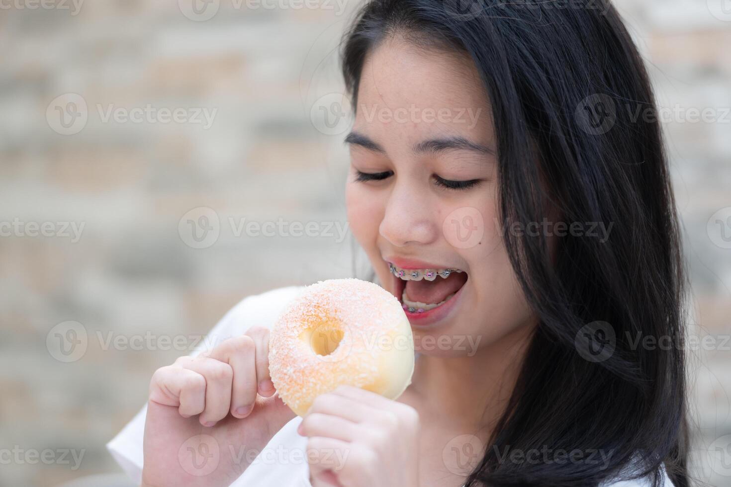 Portrait of Asian woman eating donut in the kitchen at home photo