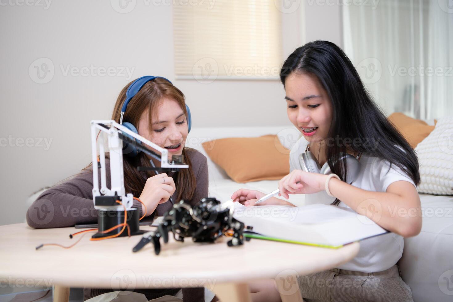 retrato de Adolescente muchachas estudiantes estudiando con robot modelo en el vivo habitación foto