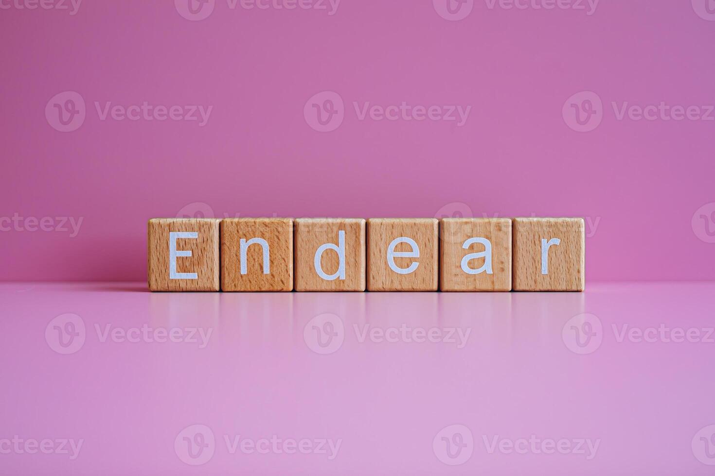 Wooden blocks form the text Endear against a pink background. photo
