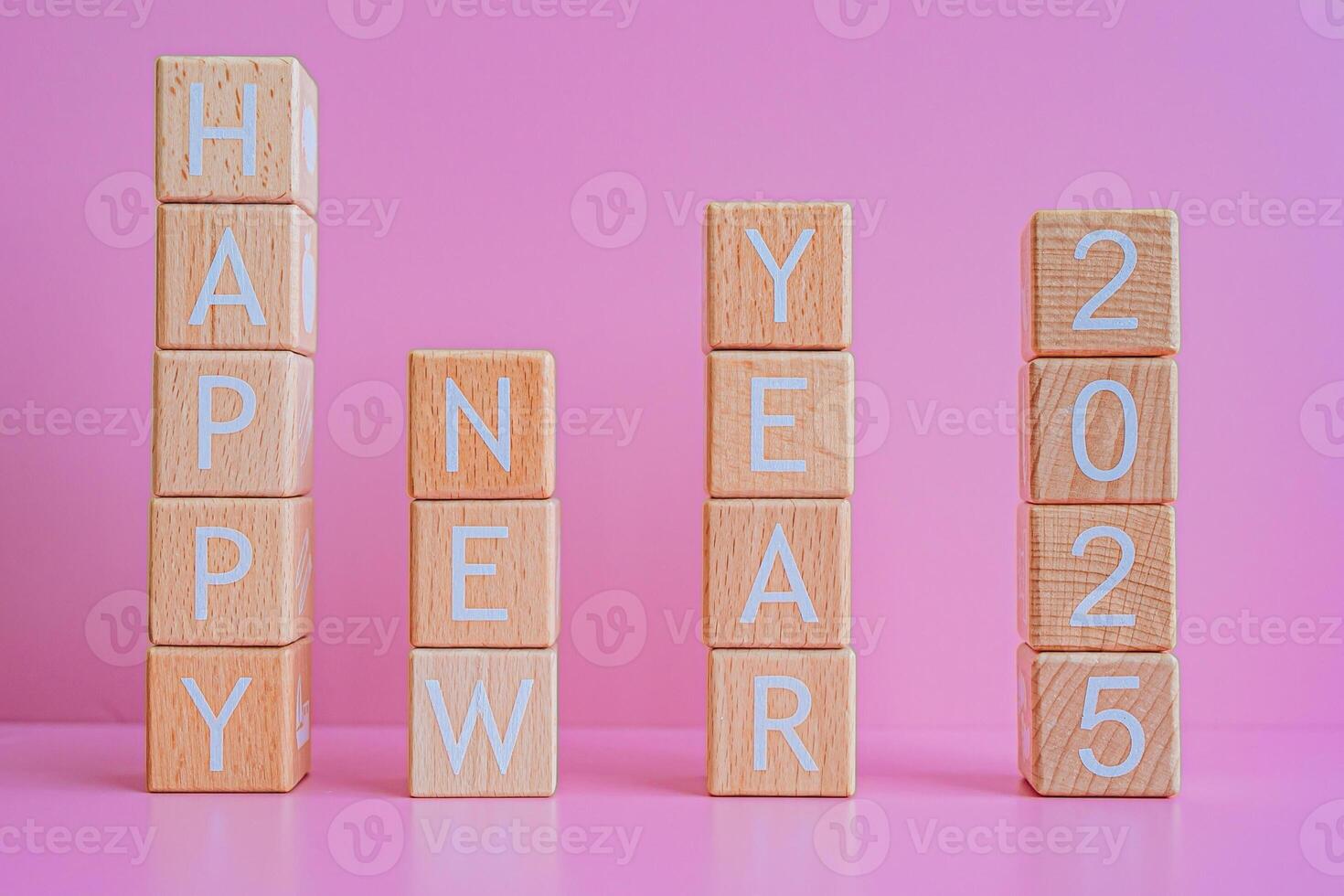 Wooden blocks form the text HAPPY NEW YEAR 2025 against a pink