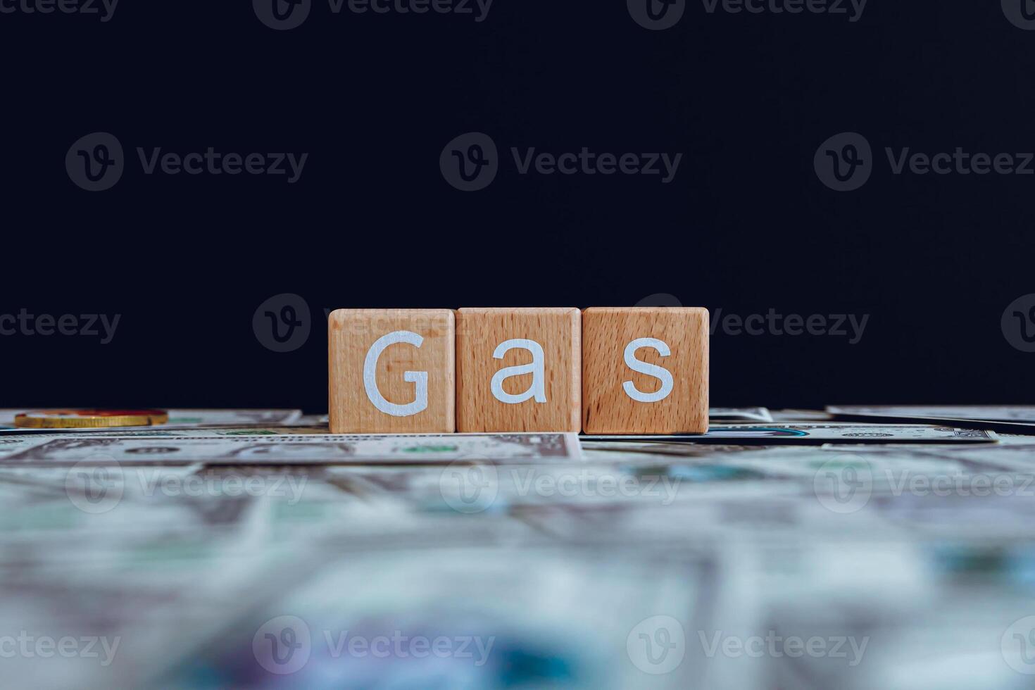 Wooden blocks with the text Gas on a black background and crypto banknotes scattered on the ground. photo