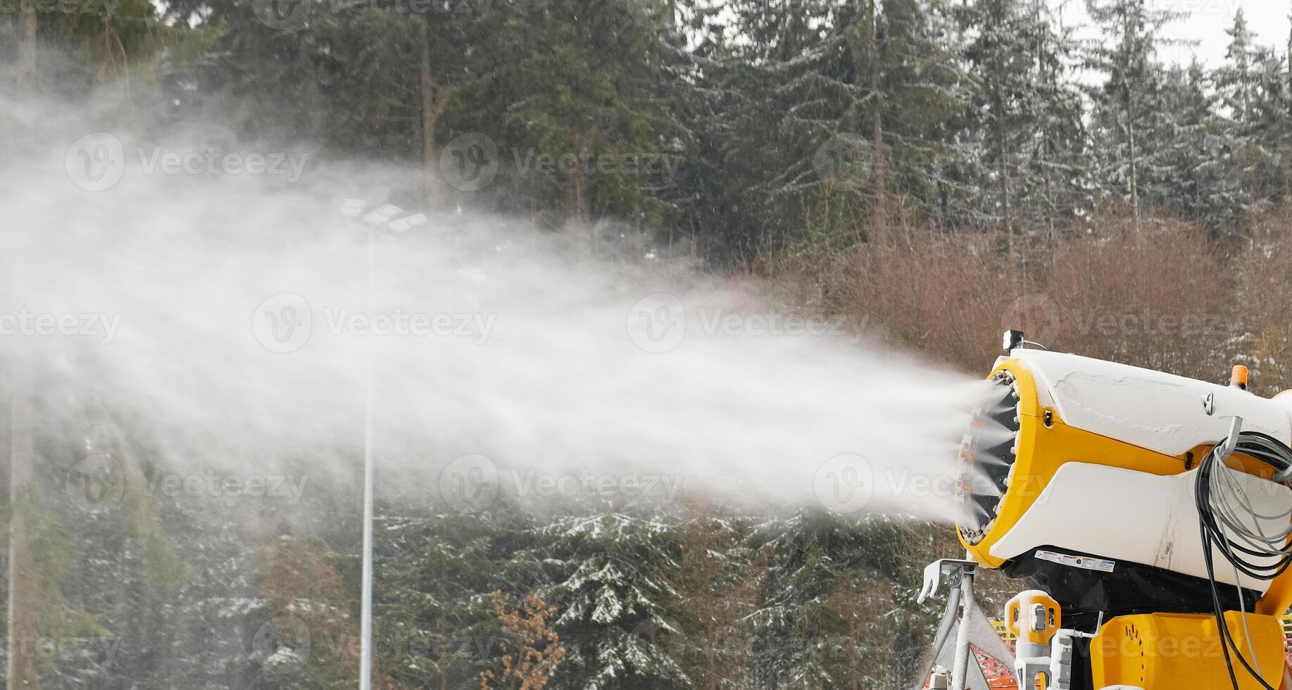 Snow cannon makes artificial snow. Snowmaking systems sprays water to produce snow. photo