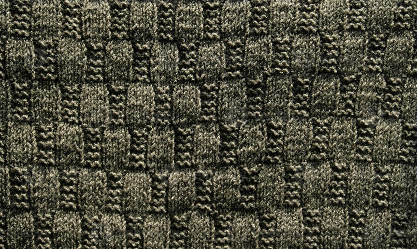 Background with gray knitted leaf shape, knitting pattern with cables. Top view, close-up. Handmade knitting wool photo