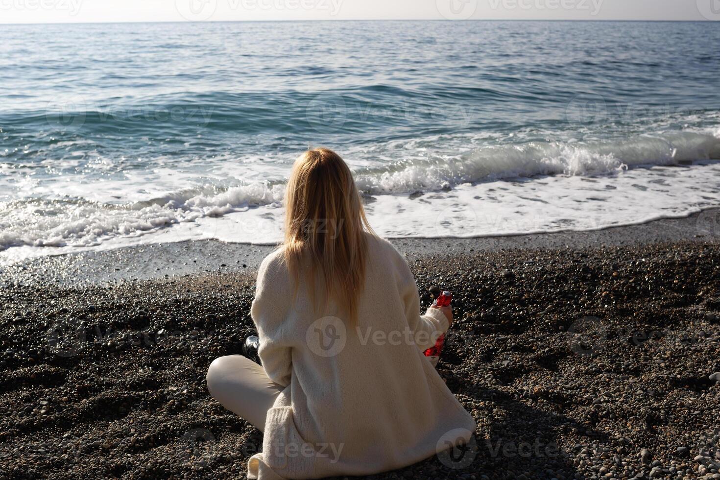 young beautiful woman on the seashore against the background of rocks photo